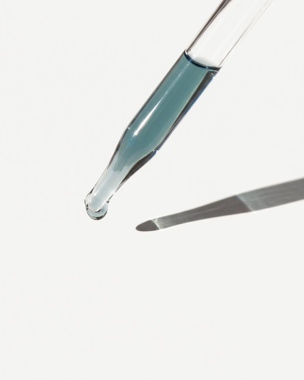 A drop of blue oil at the tip of the dropper